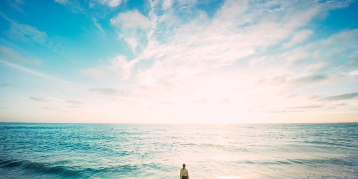 A person standing in the sea looking at the horizon.